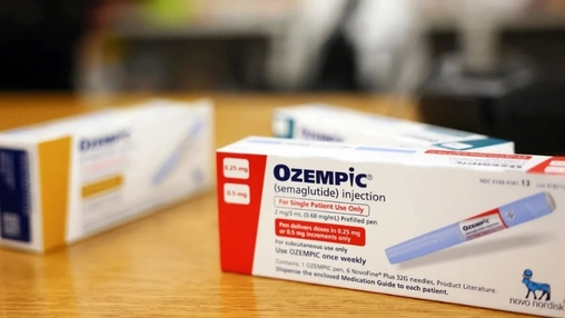 Close-up of Ozempic semaglutide prefilled injection pen beside its white and red packaging on a wooden surface